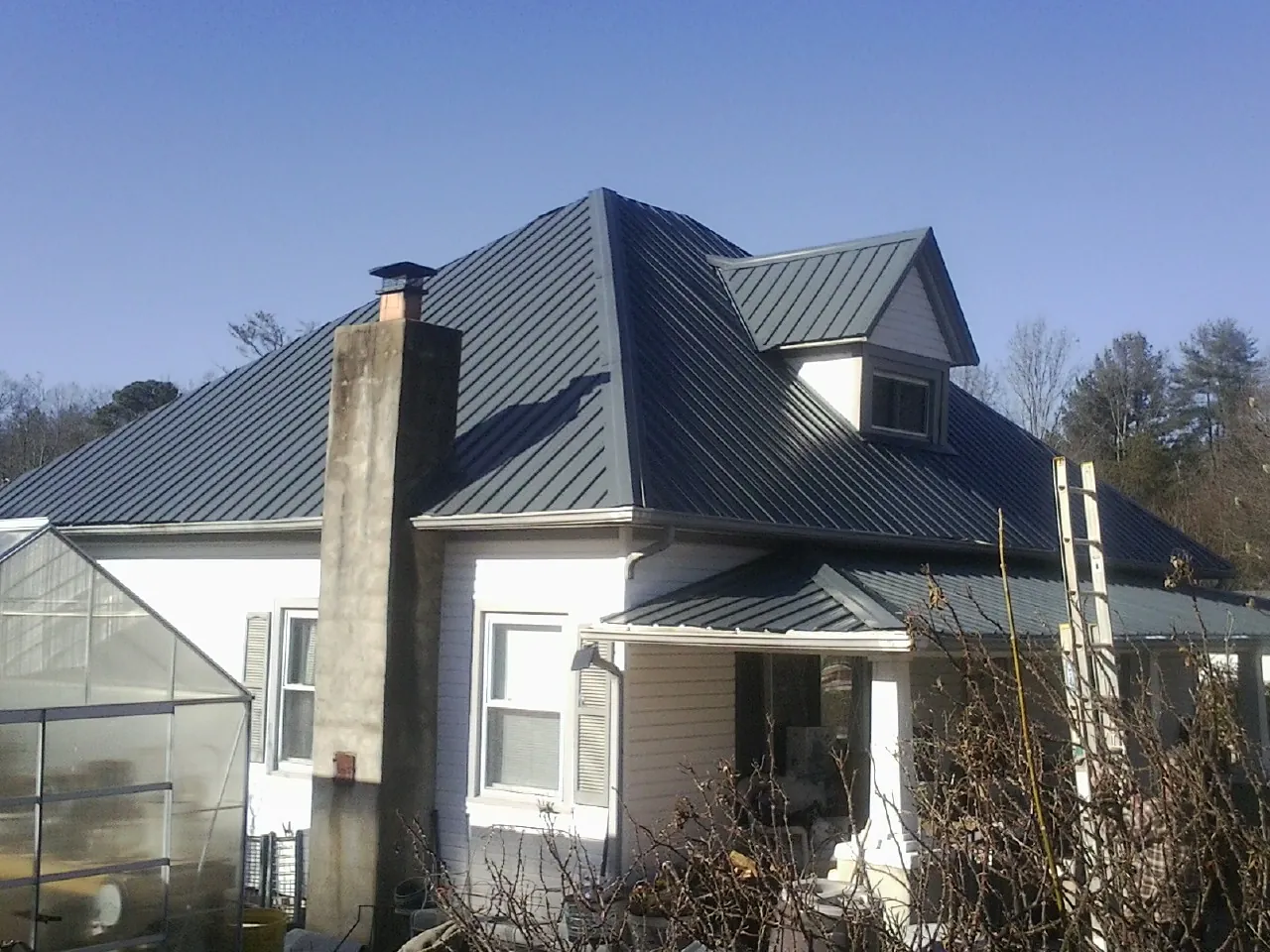 Dark blue standing seam metal roof on a white farmhouse with dormer — Slate & Tile Roof Repair by Roofing Brothers in Morning View