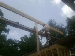 Carpenter setting a ridge beam over a new addition frame — Ice Dam Removal by Roofing Brothers in Morning View