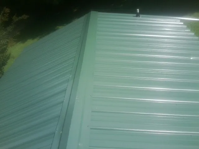 New green metal panels meeting at the ridge of a roof — Flat Roof Repair work by our crew in Morning View