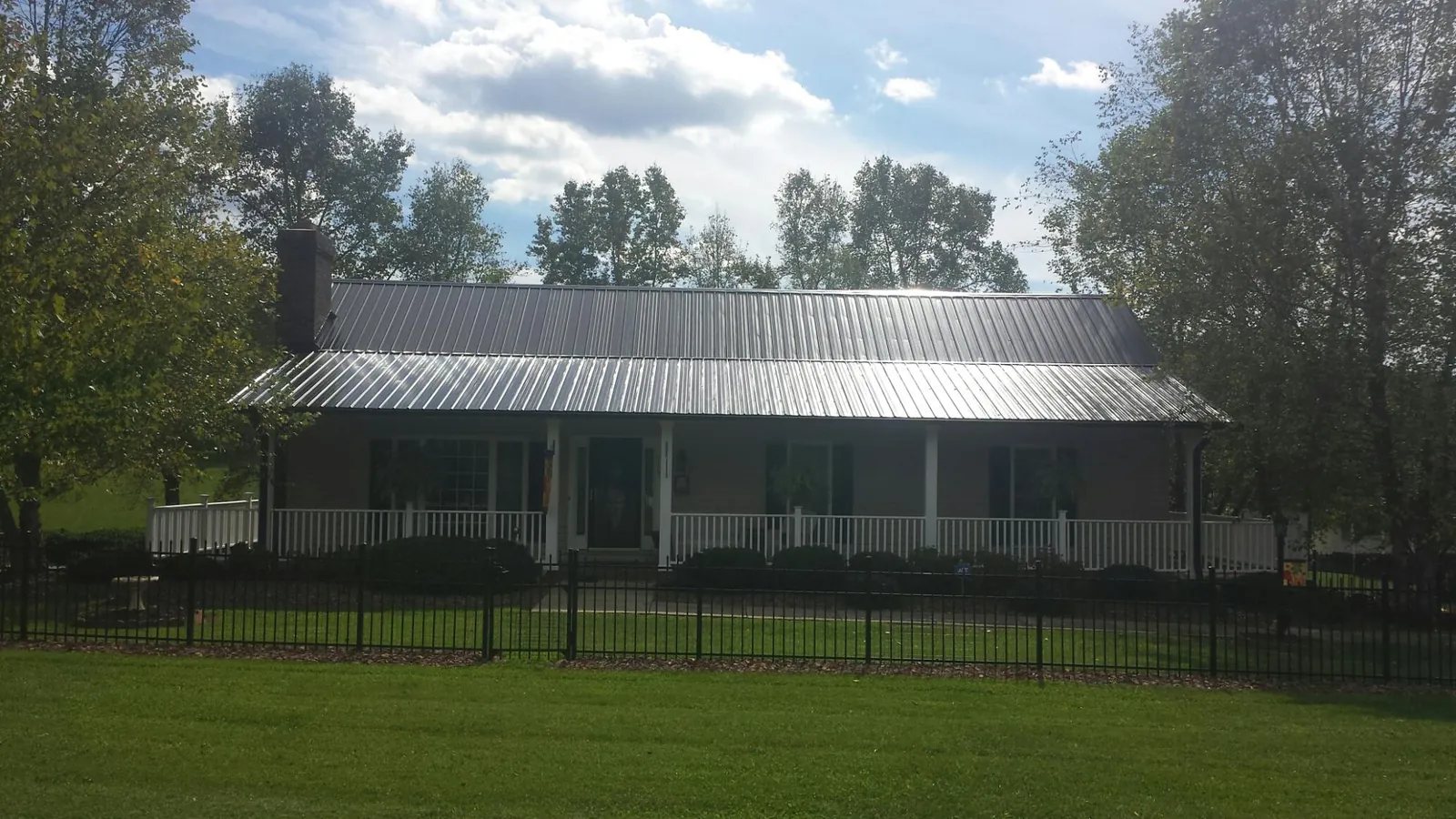 Gray metal roof on a brick ranch with a full width front porch — Gutter Guard Installation work by our crew in Morning View