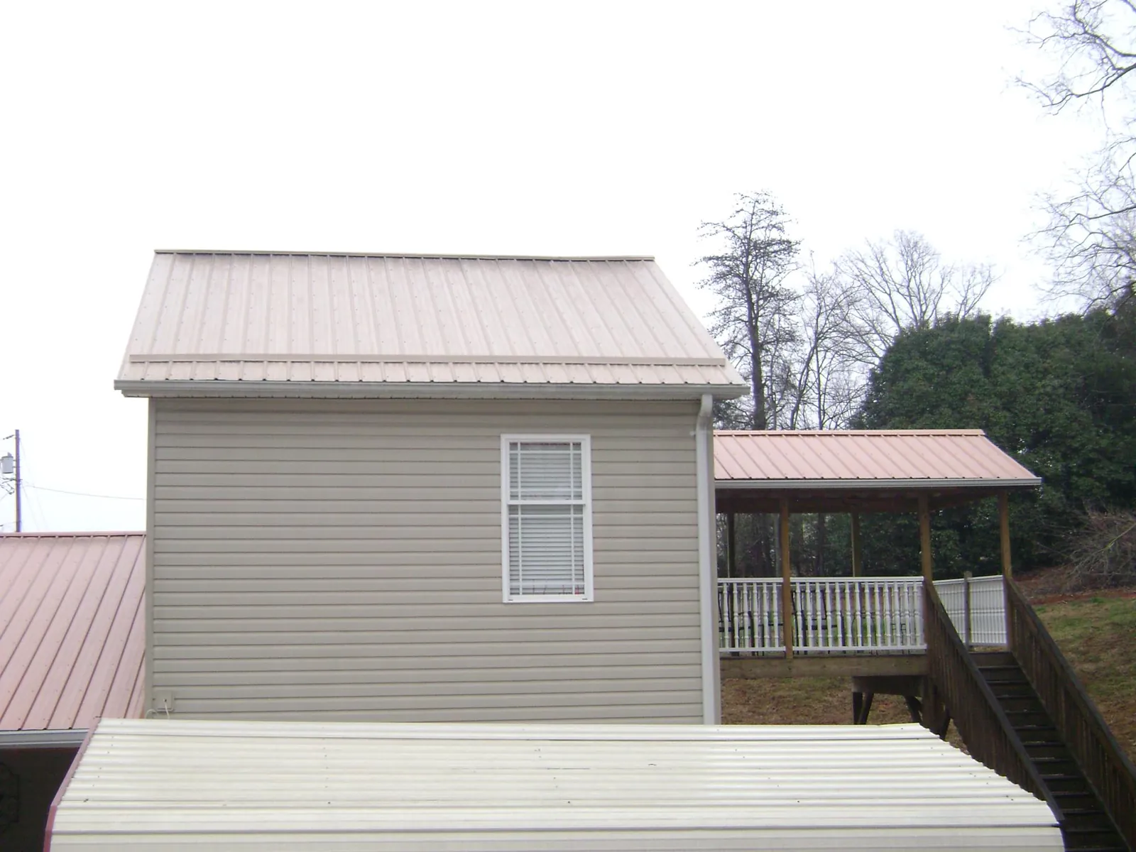 Tan metal roofs on a two story addition and attached porch, from a Roof Replacement job in Morning View