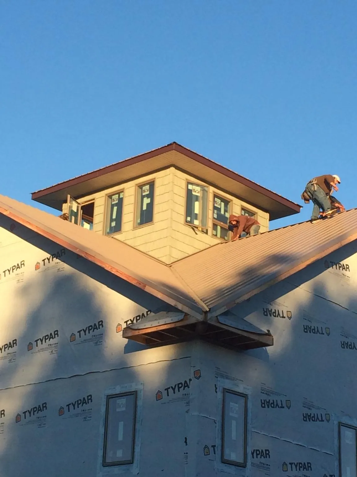 Roofers working around a rooftop cupola on a new metal roof at sunset — Roof Waterproofing in Morning View by Roofing Brothers